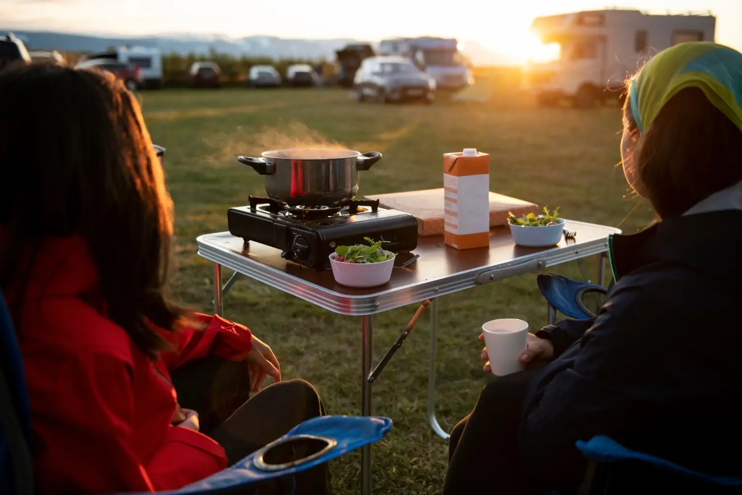 Gemeinsames Kochen an der Campingküche am Stellplatz bei Sonnenuntergang