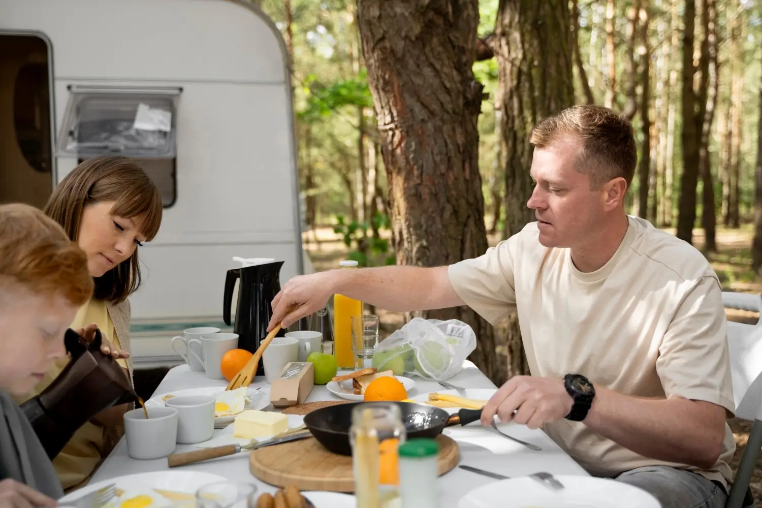 Familie beim Frühstück am Wohnwagen – entspannter Campingurlaub am Stellplatz